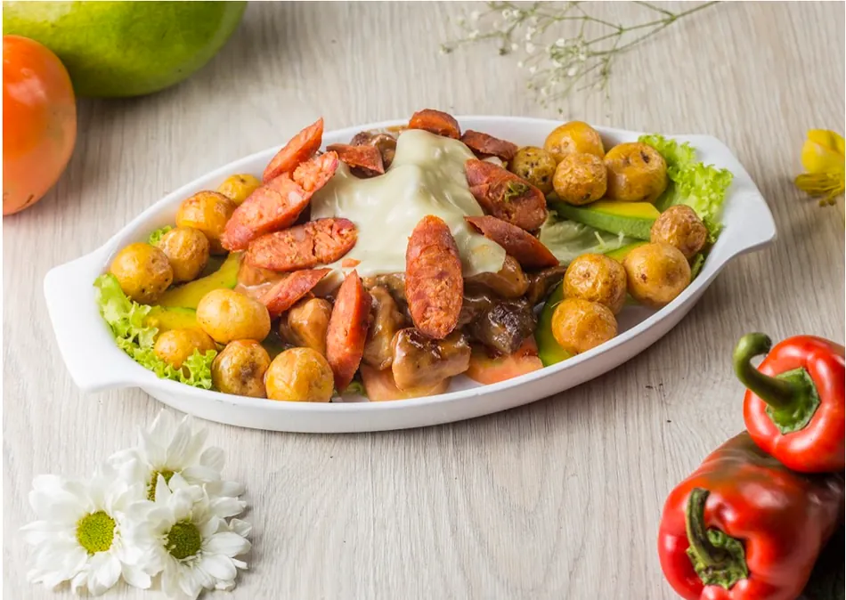 Picada de carnes con papa criolla, plátano y salsas en fuente ovalada