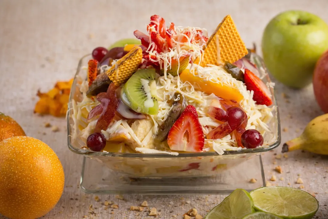 Ensalada de frutas de Rancholaos en copa de vidrio: mango, kiwi, fresa y uva con crema, queso rallado y obleas